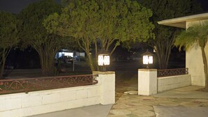 A nighttime entrance with a paved walkway, decorative metal railing, and two illuminated wall-mounted lights. - Home in North Port, AC, Wi-Fi, five minutes walk to Warm Mineral Springs  (North Port)