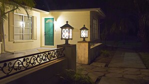 A house with a green door, two lit lanterns, and a stone pathway leading to the entrance. - Home in North Port, AC, Wi-Fi, five minutes walk to Warm Mineral Springs  (North Port)
