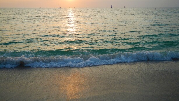 A beach with waves at sunset, boats in the distance, and a clear sky. - Home in North Port, AC, Wi-Fi, five minutes walk to Warm Mineral Springs  (North Port)