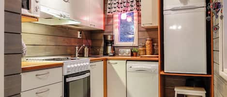 Cozinha compacta com armários brancos, fogão, lava-louças e geladeira.