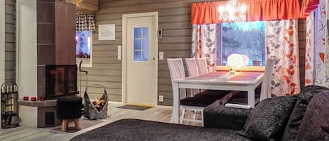 A cozy living room with a fireplace, a dining table with chairs, and a sofa.