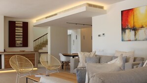 Una sala moderna con sofá, dos sillones, una mesita de centro y un comedor con mesa y sillas.