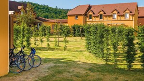 Un patio con un sendero, bicicletas y un edificio de techo rojo.