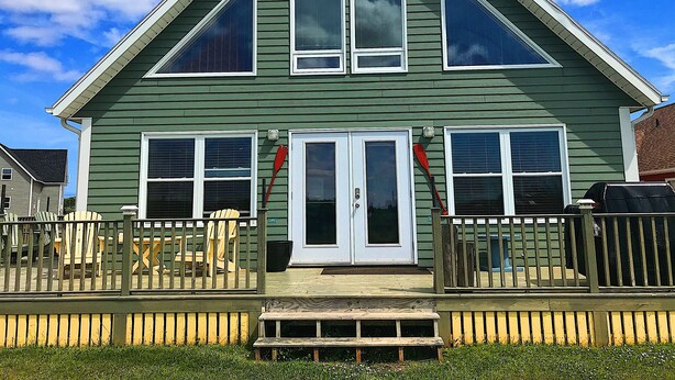 A two-story house with a front porch, large windows, and a garage. - Cavendish Driftwood Getaway - Beach, National Park, Nature Trails, Seafood, Golf (Cavendish)