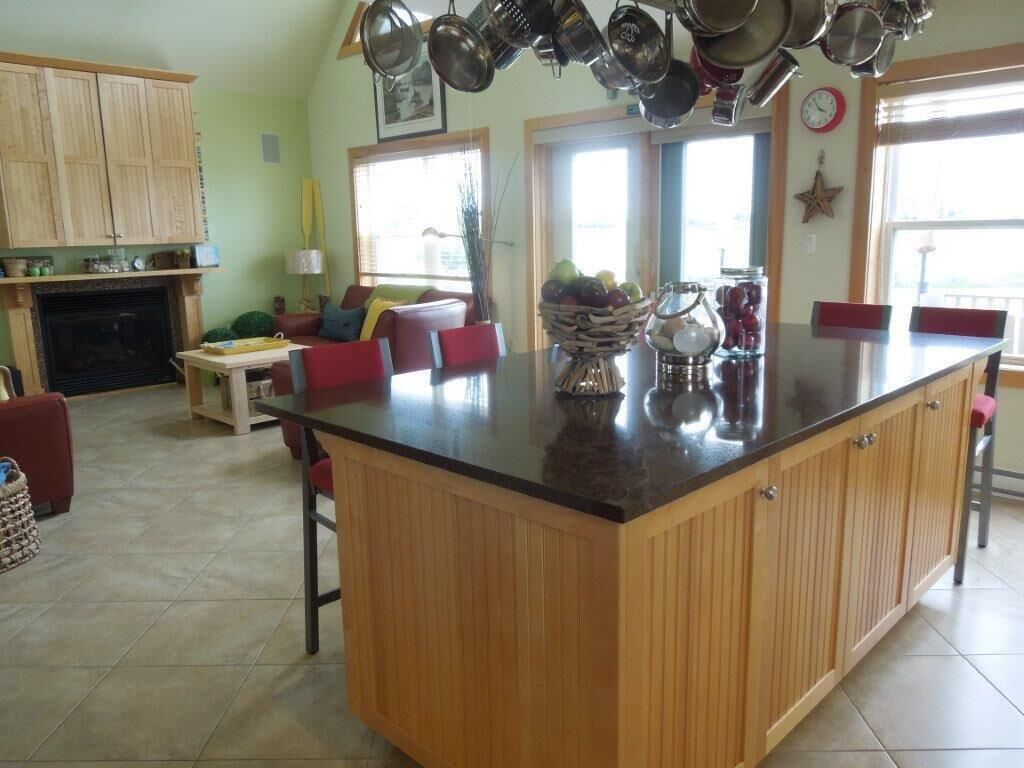 A kitchen with wooden cabinets, a central island, and a dining area with red chairs.