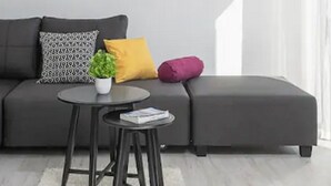 A modern living room with a grey sofa, a small round table, and a potted plant.
