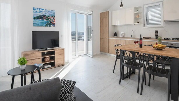 A modern apartment with a living room, dining area, kitchen, and balcony.