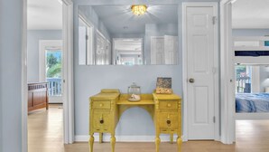 Een slaapkamer met een stapelbed, een gele dressoir, een grote spiegel en een deur naar een andere kamer.