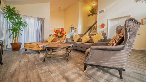 A spacious living room with a sofa, armchair, and coffee table, a staircase, and a potted plant. - Entire house, pool, minutes to strip, Sleeps 10! Only 3 miles away from Strips (Las Vegas)