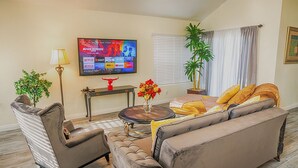 A living room with a sofa, armchair, coffee table, TV, and decorative items. - Entire house, pool, minutes to strip, Sleeps 10! Only 3 miles away from Strips (Las Vegas)