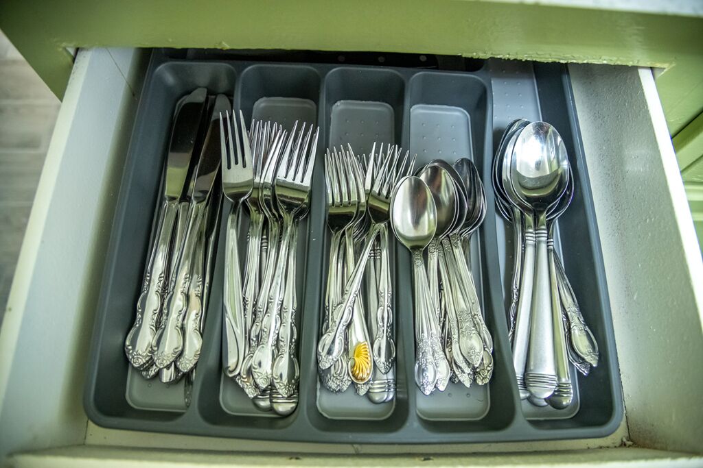 A drawer with multiple compartments containing various silverware items.