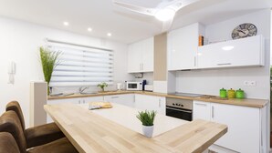 Eine moderne Küche mit weißen Schränken, einer Holz Arbeitsplatte und einer zentralen Kochinsel.