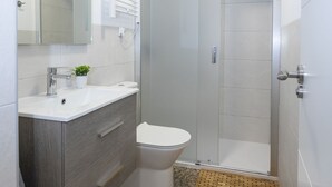Ein modernes Badezimmer mit einem weißen Waschbecken, einer Toilette und einer Duschkabine aus Glas.