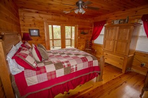 Ein Schlafzimmer einer Holzhütte mit Bett, Deckenventilator, Fenster und Holzschrank.
