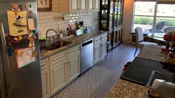A kitchen with white cabinets, a granite countertop, a stainless steel refrigerator, and a window with a view of greenery. - Private home minutes from Siesta Key and Downtown Sarasota. (Sarasota)