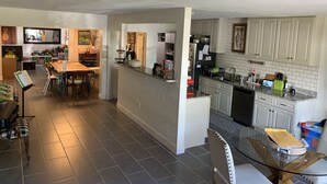 A spacious kitchen with modern appliances, a dining area with a long table, and a living space with a TV and artwork. - Private home minutes from Siesta Key and Downtown Sarasota. (Sarasota)