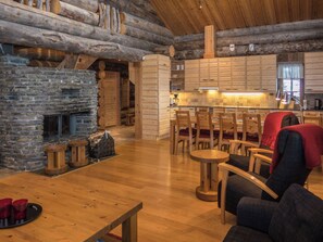 A rustic interior with a stone fireplace, wooden furniture, and a kitchen area.