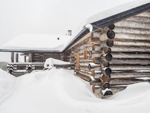 Een blokhut met een met sneeuw bedekte dak en muren, omringd door sneeuw.
