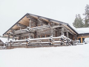 Een blokhut met een sneeuwbedekte buitenkant, houten blokken en een houten veranda.
