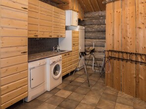 Een kleine keuken met houten kastjes, een wasmachine en een metalen droogrek.
