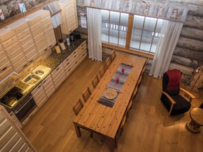 Un intérieur en bois comprenant une cuisine, un coin repas et une fenêtre avec des rideaux.