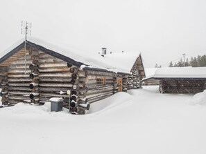 A log cabin with a chimney, a wooden door, and a snow-covered roof.