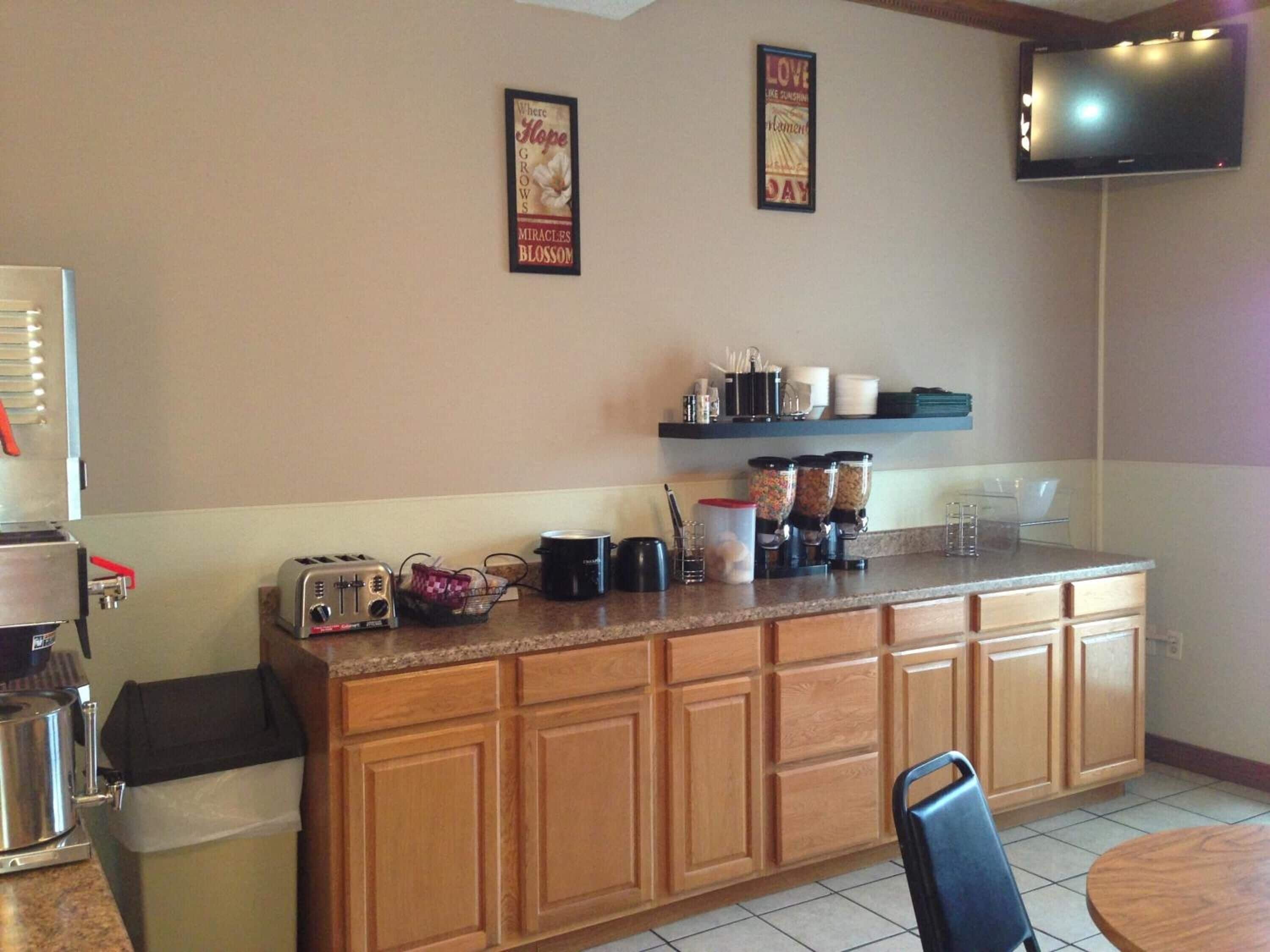 A kitchen with wooden cabinets, a countertop with coffee makers, a toaster, and a trash bin.
