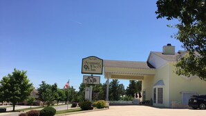 A hotel named Spinning Wheel Inn with a signboard, a covered parking area, and a lawn. - Spinning Wheel Inn Branson (Branson)