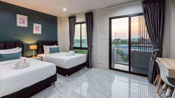 A hotel room with two beds, a balcony, and a dining area. - The Living Hotel SamutPrakan (Bang Bo)