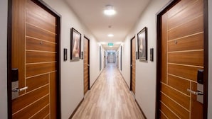 A hotel hallway with wooden doors and a tiled floor. - The Living Hotel SamutPrakan (Bang Bo)