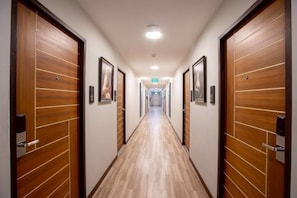 Un couloir d’hôtel avec des portes en bois et un sol carrelé.