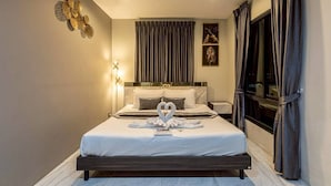 A hotel room with a bed, a nightstand, a wall-mounted light fixture, and a window with curtains. - The Living Hotel SamutPrakan (Bang Bo)