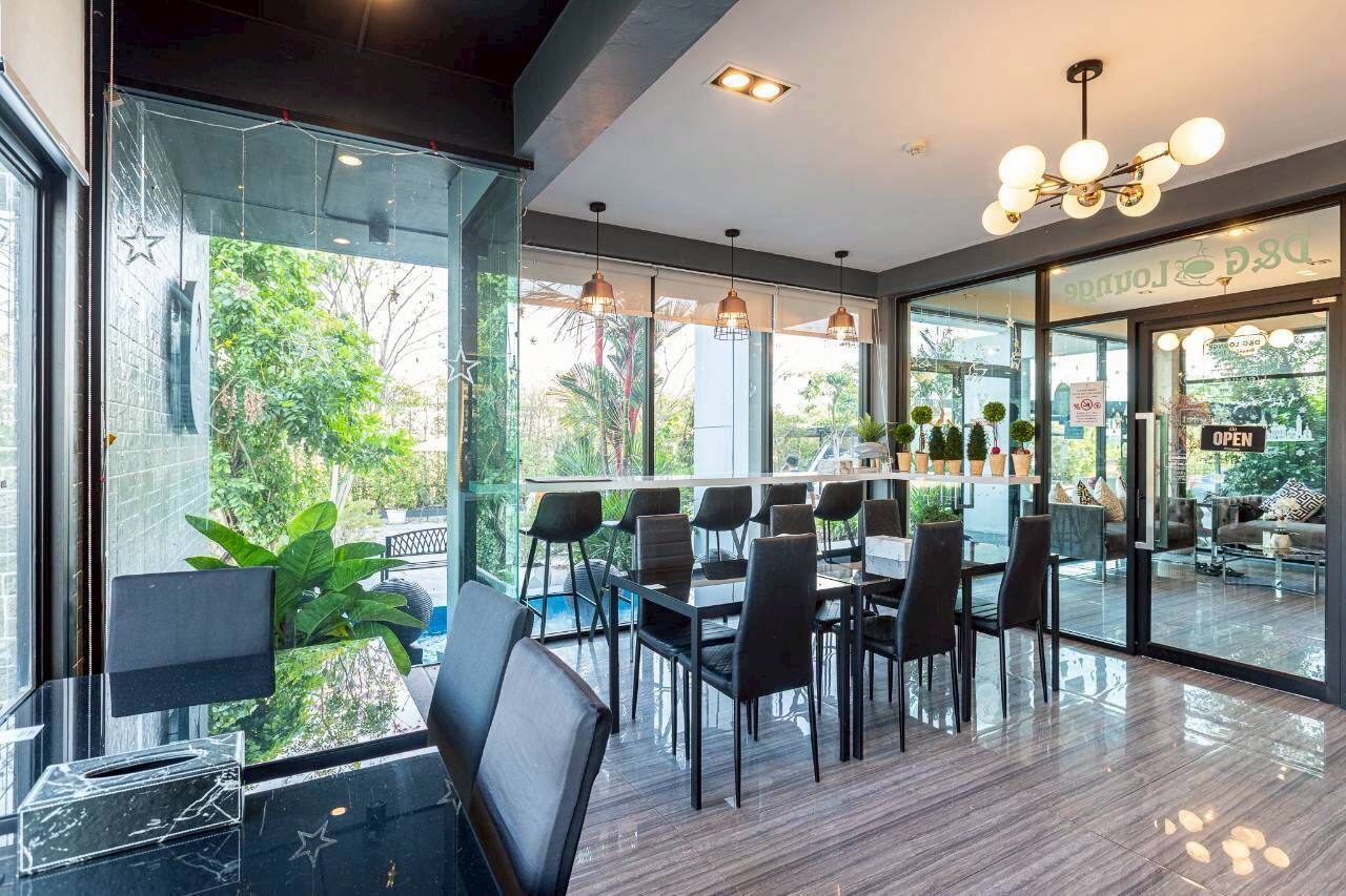 A modern indoor space with a glass wall, black chairs, and a wooden floor.