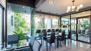 A modern indoor space with a glass wall, black chairs, and a wooden floor. - The Living Hotel SamutPrakan (Bang Bo)