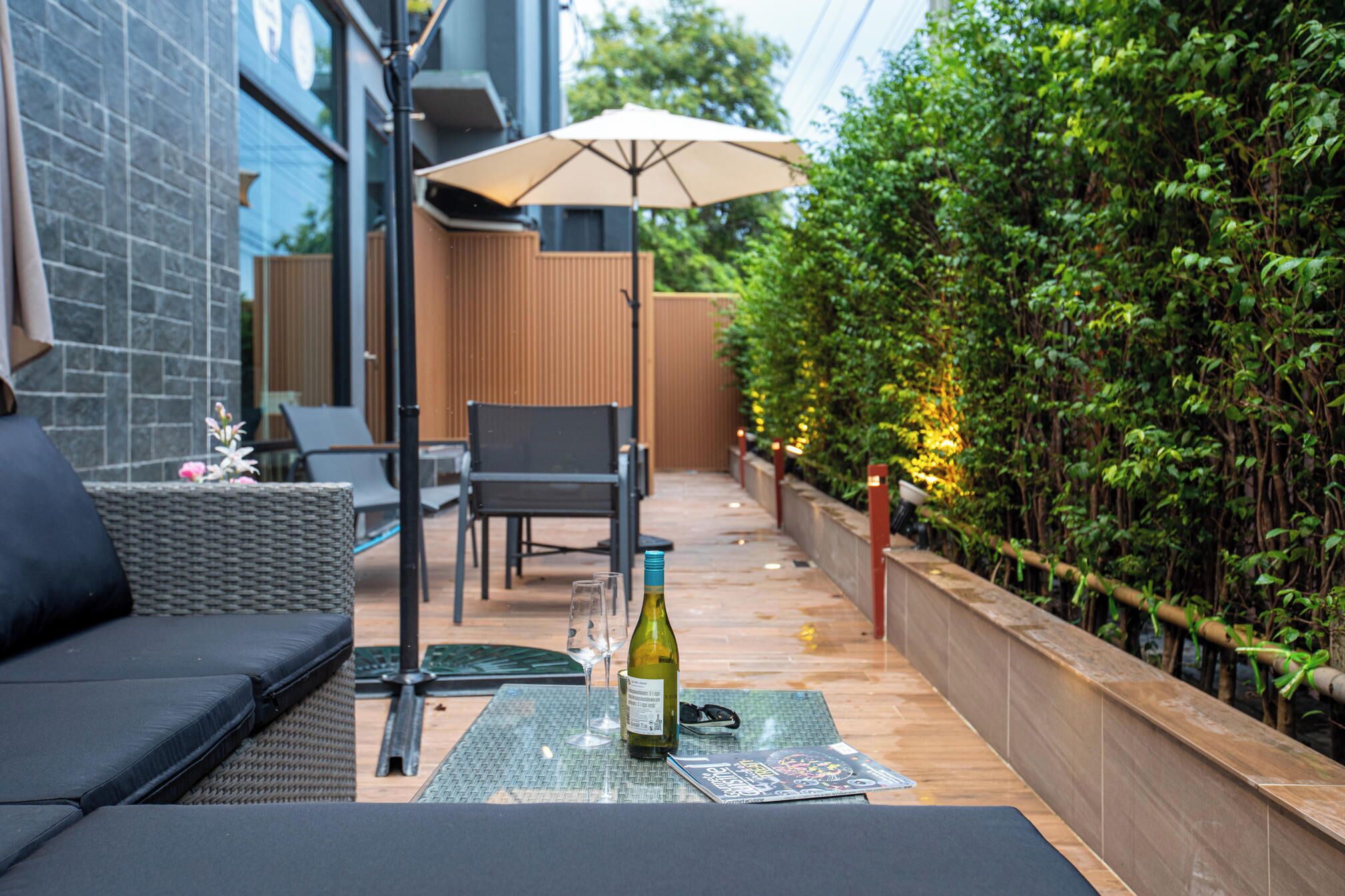 An outdoor seating area with a table, chairs, and a bottle of wine.