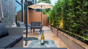 An outdoor seating area with a table, chairs, and a bottle of wine.