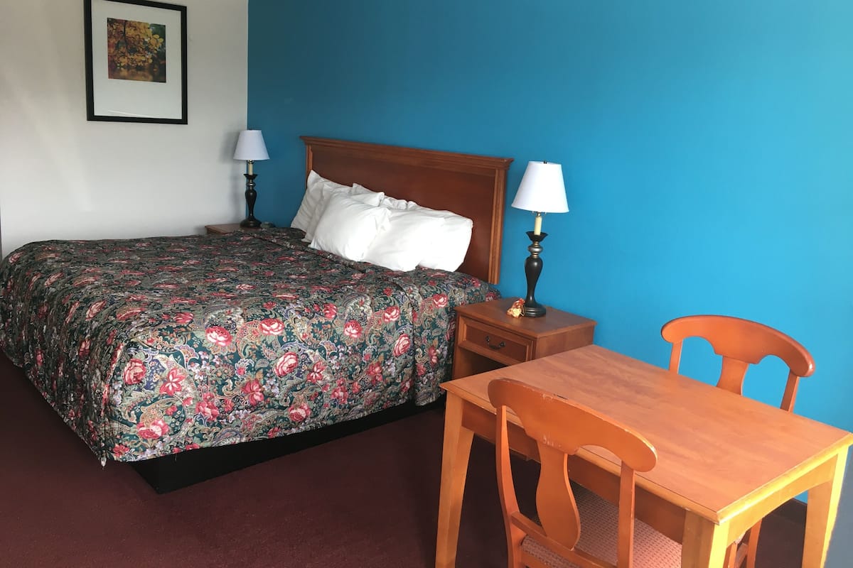 Une chambre à coucher comprenant un lit, des tables de chevet, une lampe, une chaise et une table.