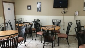 A dining area with round tables and black metal chairs, a television mounted on the wall, and a door with a 'Not an Exit' sign. - Twelve Oaks Inn (Branson)