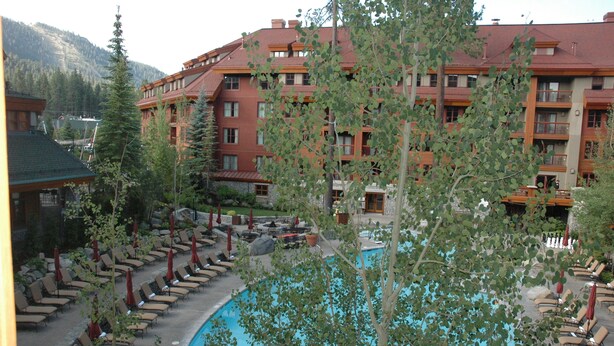 Ein Hotel mit Poolbereich, Sitzgelegenheiten im Freien und einer Bergkulisse.