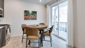 A modern kitchen with a gas stove, a dining table with four chairs, and a large window with a view of a balcony.