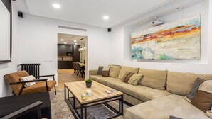 Ein modernes Wohnzimmer mit einer Couch, einem Couchtisch und einem Essbereich im Hintergrund.