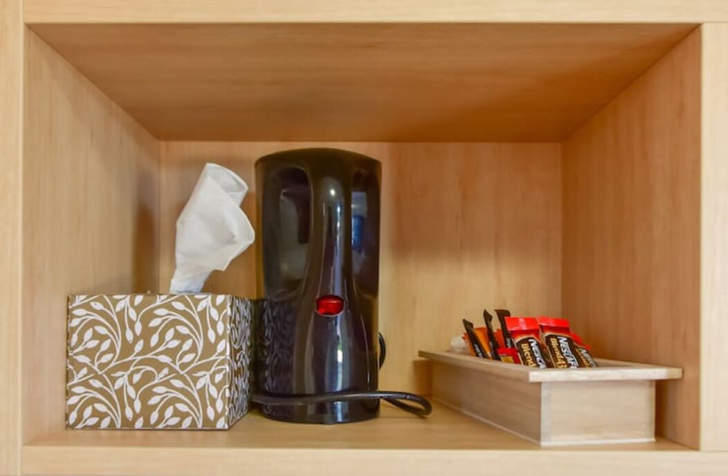 Un mueble de madera con una cafetera, un dispensador de pañuelos y un organizador de especias.