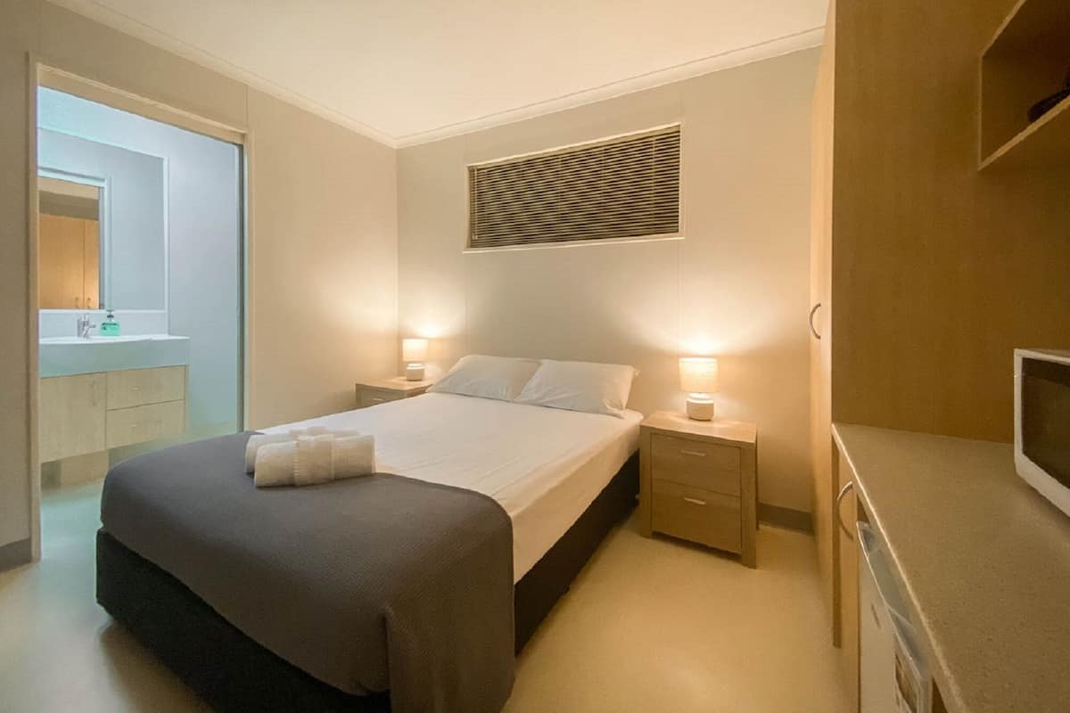 A modern bedroom with a bed, bedside tables, a mirror, and a TV.