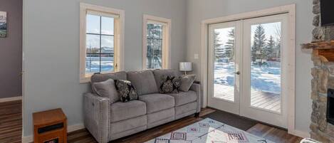 A cozy living room with a grey sofa, a patterned rug, and a stone fireplace.