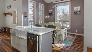 Una cocina con una isla grande, suelo de madera y un comedor con sillas y una mesa.