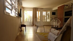 A spacious living area with a sofa, two white chairs, a small table, and a fan. - From the beach to golf (Saint-Gilles-les Bains)