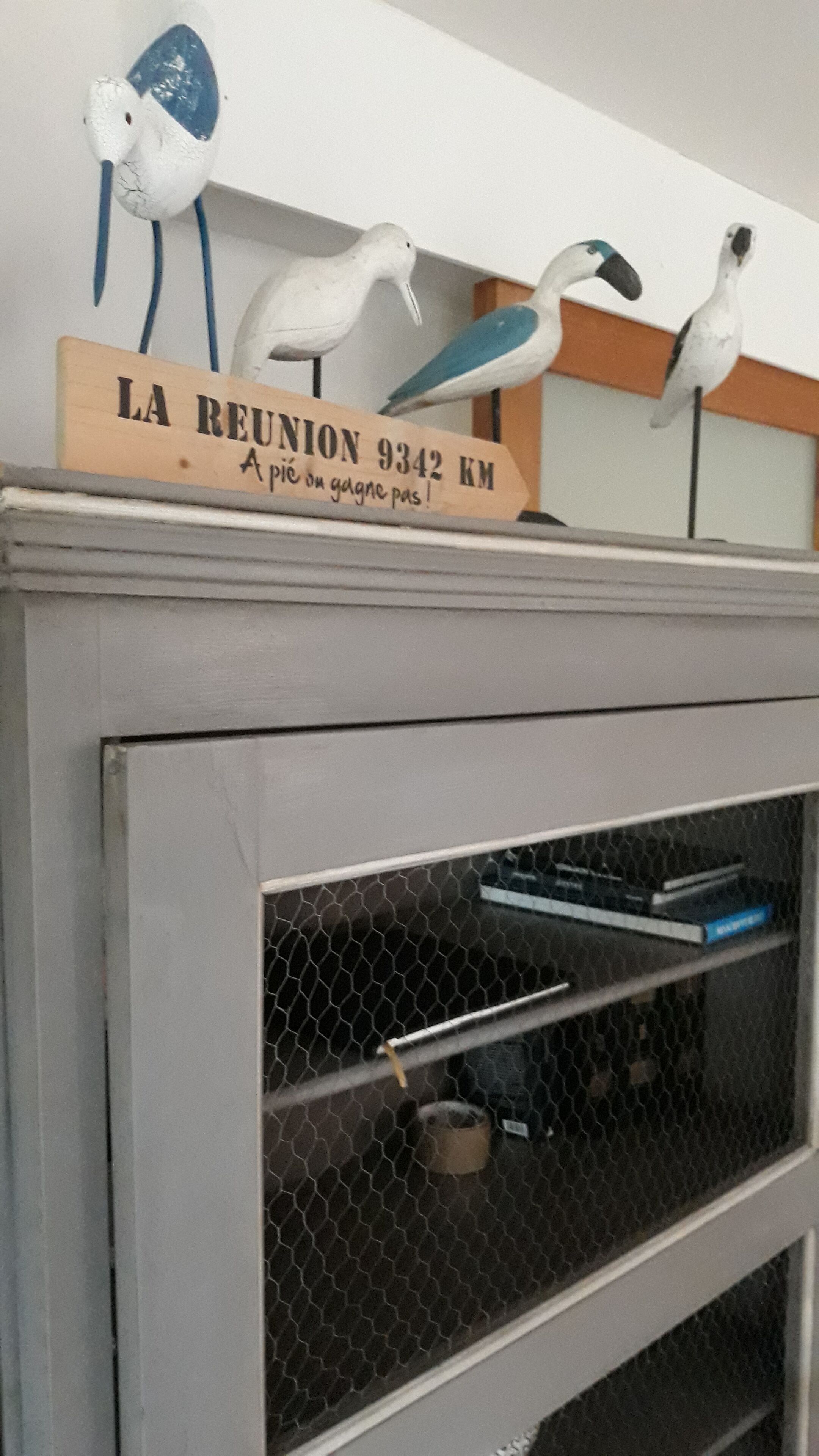 Una jaula de pájaros con un letrero de madera encima.