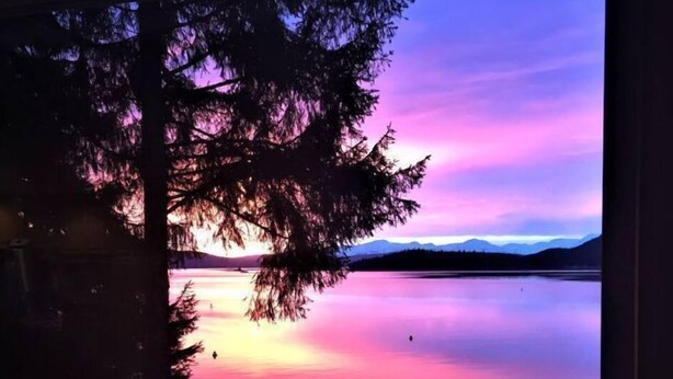 A view from a balcony overlooking a calm lake with mountains in the distance and a twilight sky. - Eagles Watch Ocean Front B and B, Auke Bay, Juneau
 CBJ 1000195 (Juneau)