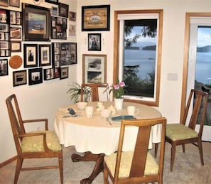 A dining area with a round table, chairs, and a window with a view of the sea.