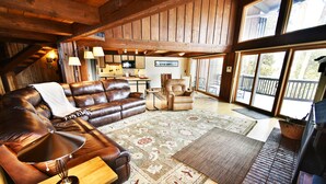 A spacious living room with a leather sofa, a wooden coffee table, and a large rug. There is a fireplace and a dining area visible in the background. - Near Trails! Big Deck! Easy Drive to Dining, Events, Activities, Lake (Silverthorne)